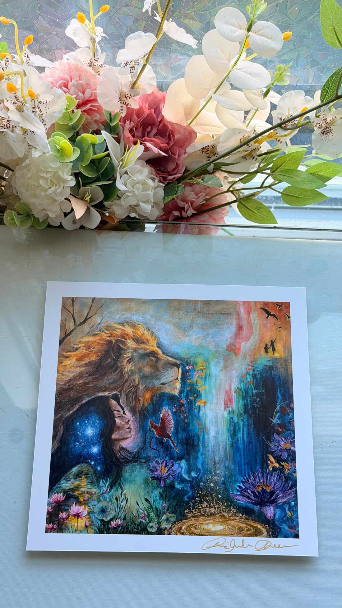 Colorful artwork of a lion with fantasy elements held by a hand against a blurred background.