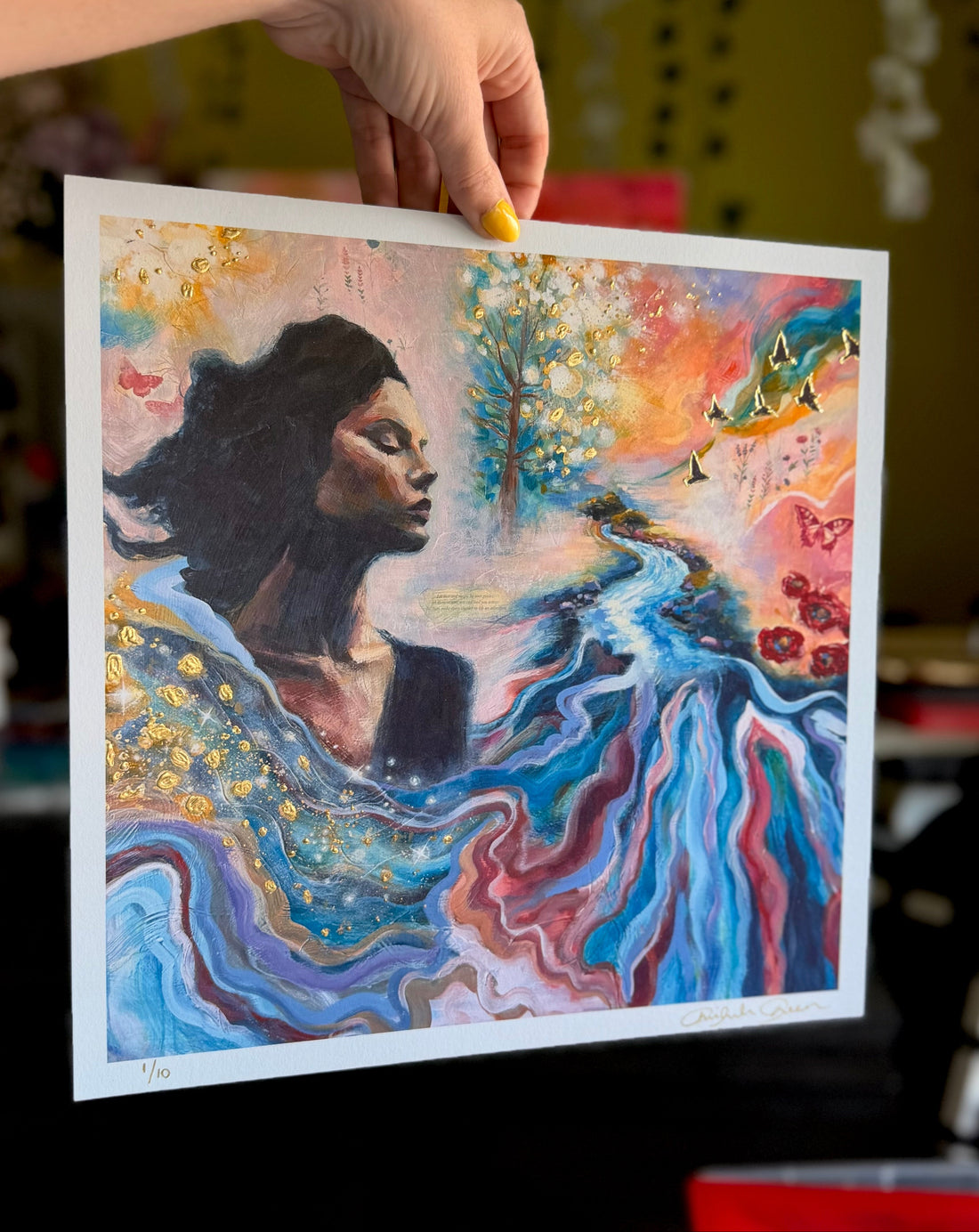 Colorful artwork of a woman with nature elements held by a hand.