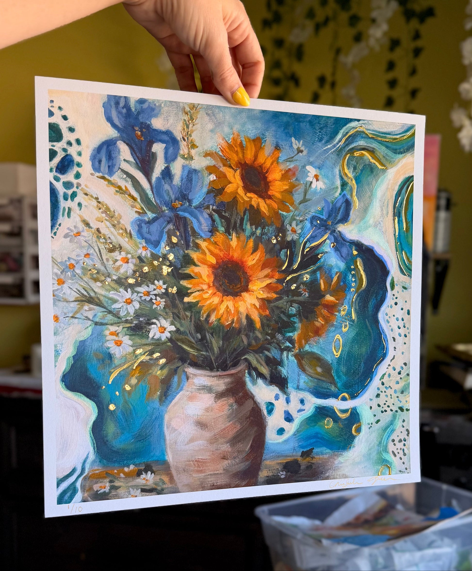 Card with a floral design featuring sunflowers and blue flowers held by a hand.