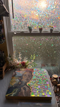 Mosaic artwork on a table with a window in the background