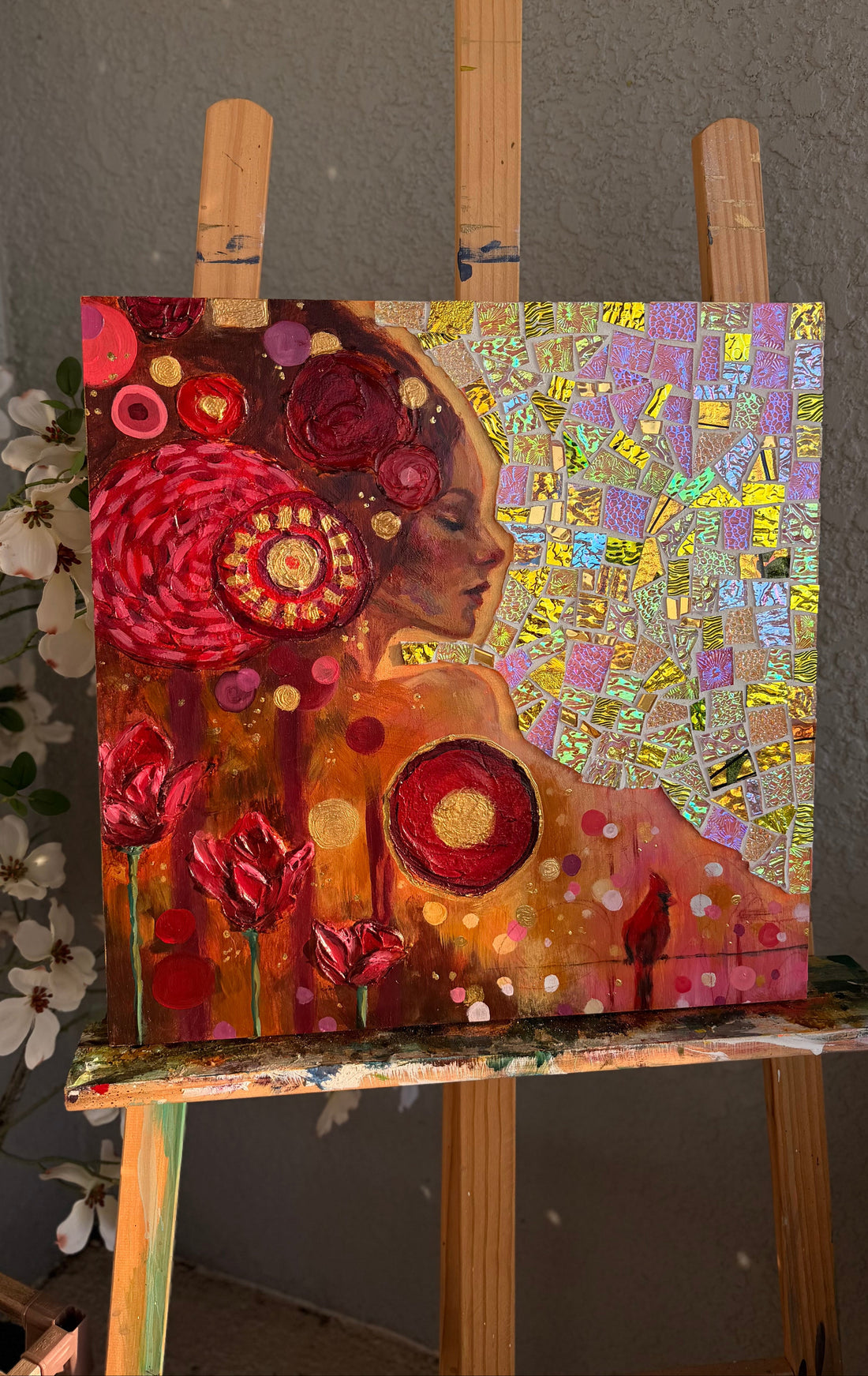 Two abstract artworks on an easel against a gray wall.