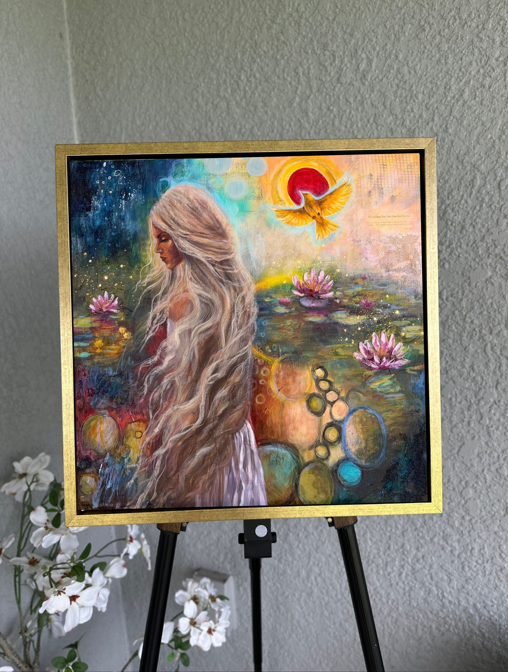 Colorful painting of a woman with long hair in a pond setting on an easel.